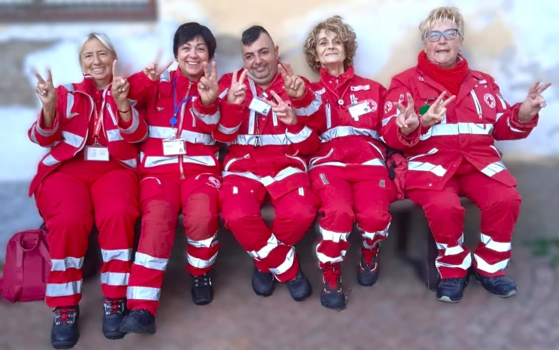 Cinque volontari del Comitato di Valceresio in divisa, seduti insieme e sorridenti